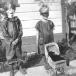 Boy and girl dressed in costume, possibly for Halloween. Black cat in baby doll stroller. Circ. 1920 William S. Borba Collection from Ed Trigiero.